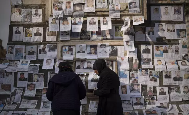 Women look at photos of people reported to be missing by members of ousted Syrian President Bashar Assad's army, or a pro-government militia, in the Marjeh square in Damascus, Syria, Sunday, Dec. 22, 2024. (AP Photo/Leo Correa)