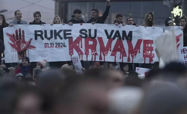 People hold a banner that reads "You have blood on your hands" during a protest against the Serbian authorities in Belgrade, Serbia, Sunday, Dec. 22, 2024. (AP Photo/Darko Vojinovic)