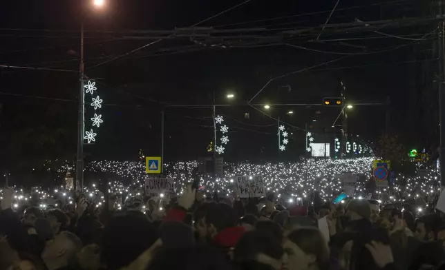 People hold their mobile phones during a protest against populist President Aleksandar Vucic and his government, whose tight grip on power has been challenged by weeks of street protests led by university students, in Belgrade, Serbia, Sunday, Dec. 22, 2024. (AP Photo/Marko Drobnjakovic)