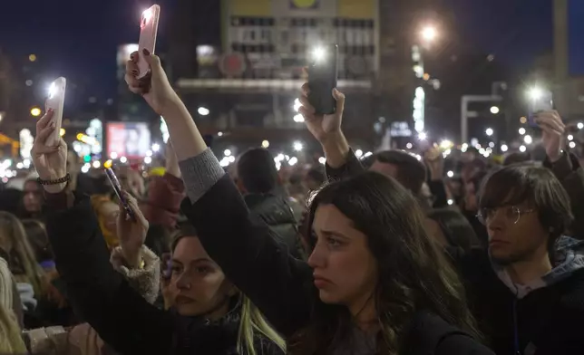 People use lights on their mobile phones during a protest against populist President Aleksandar Vucic and his government, whose tight grip on power has been challenged by weeks of street protests led by university students, in Belgrade, Serbia, Sunday, Dec. 22, 2024. (AP Photo/Marko Drobnjakovic)