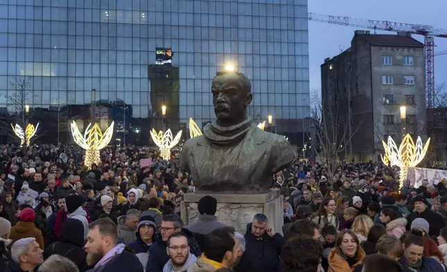 People gather around the bust of Dimitrije Tucovic, early 20th century Serbian socialist politician, during a protest against populist President Aleksandar Vucic and his government, in central Belgrade, Serbia, Sunday, Dec. 22, 2024. (AP Photo/Marko Drobnjakovic)