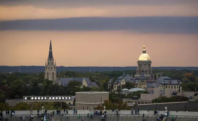 FILE - Fans file out of the stadium as clouds approach the Golden Dome and Basilica of the Sacred Heart on Oct. 12, 2024, in South Bend, Ind. (AP Photo/Michael Caterina, File)