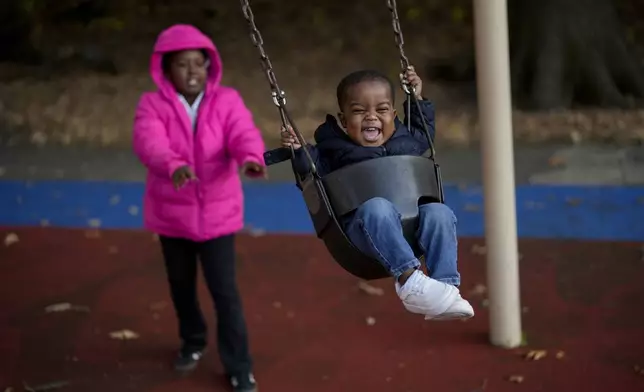 Makhi Chillis, 2, smiles as he is pushed in a swing by his sister Myla Chillis, 9, Monday, Dec. 2, 2024, in Memphis, Tenn. (AP Photo/George Walker IV)