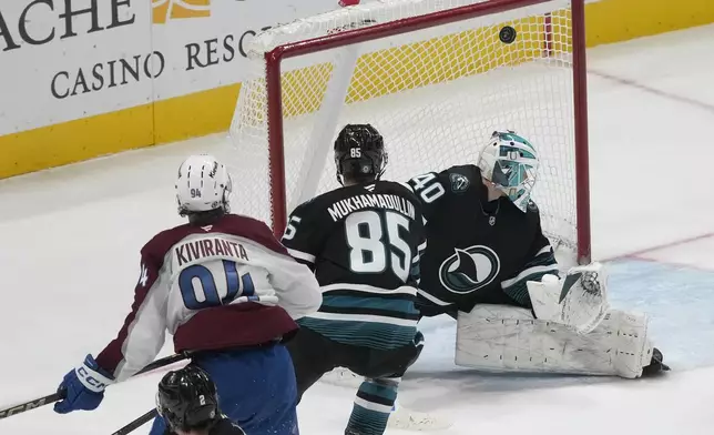 Colorado Avalanche left wing Joel Kiviranta, left, and San Jose Sharks defenseman Shakir Mukhamadullin (85) watch as Kiviranta scores a goal past goaltender Alexandar Georgiev, right, during the third period of an NHL hockey game in San Jose, Calif., Thursday, Dec. 19, 2024. (AP Photo/Jeff Chiu)