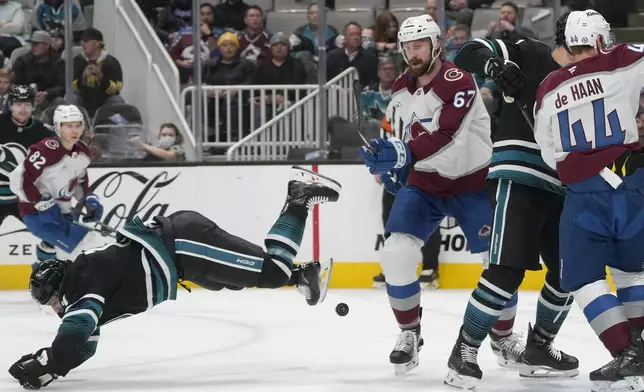 San Jose Sharks center Luke Kunin, left, falls forward next to Colorado Avalanche defenseman Keaton Middleton (67) during the first period of an NHL hockey game in San Jose, Calif., Thursday, Dec. 19, 2024. (AP Photo/Jeff Chiu)