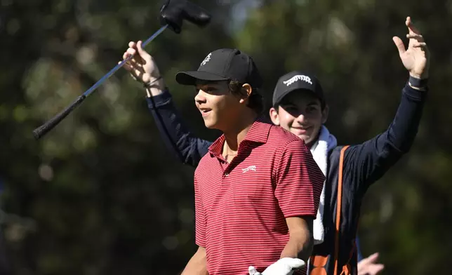 Charlie Woods, front, and his caddie Luke Wise react after his hole-in-one on the fourth hole during the final round of the PNC Championship golf tournament, Sunday, Dec. 22, 2024, in Orlando, Fla. (AP Photo/Phelan M. Ebenhack)