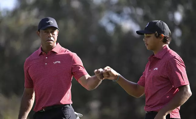 Tiger Woods, left, and his son Charlie Woods fist bump after making their putt on the 13th green during the final round of the PNC Championship golf tournament, Sunday, Dec. 22, 2024, in Orlando, Fla. (AP Photo/Phelan M. Ebenhack)