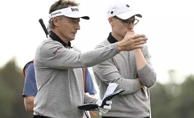 Bernhard Langer, left, and his son Jason Langer, right, discuss their shots before putting on the 14th green during the final round of the PNC Championship golf tournament, Sunday, Dec. 22, 2024, in Orlando, Fla. (AP Photo/Phelan M. Ebenhack)