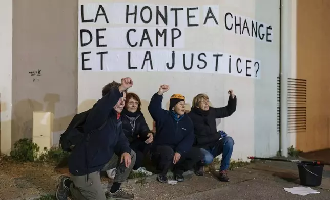 Members of the feminist collective "Les Amazones Avignon" stand by a message of support for Gisele Pelicot reading "Shame has changed side, what about justice ?" during their action of collage of messages around the courthouse where the Mazan rape trial is taking place in Avignon, France, Wednesday, Dec. 18, 2024. (AP Photo/Lewis Joly)