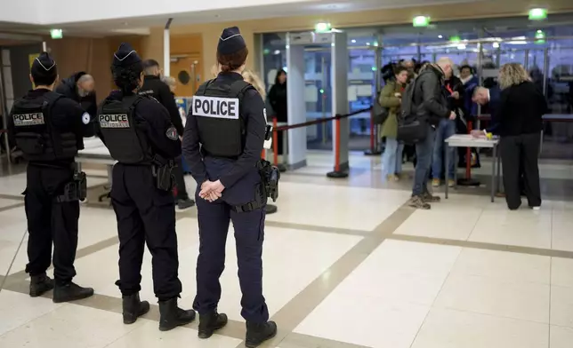 Police officers stand guard inside the courthouse of Avignon during the trial of four dozen men charged with aggravated rape and sexual assault on Gisèle Pelicot, in Avignon, southern France, Thursday, Dec. 19, 2024. (AP Photo/Lewis Joly)