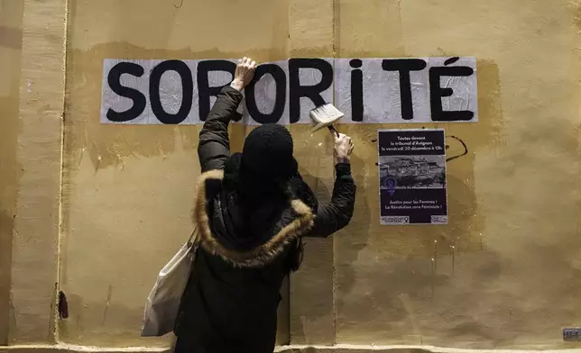 A member of the feminist collective "Les Amazones Avignon" sticks a message of support for Gisele Pelicot reading "Sorority" around the courthouse where the Mazan rape trial is taking place in Avignon, France, Wednesday, Dec. 18, 2024. (AP Photo/Lewis Joly)