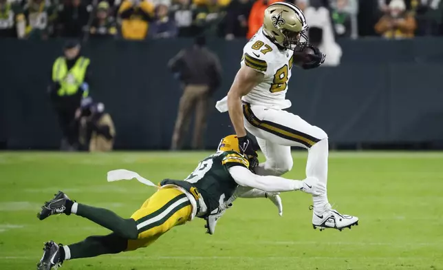 New Orleans Saints tight end Foster Moreau (87) carries against Green Bay Packers safety Zayne Anderson during the first half of an NFL football game, Monday, Dec. 23, 2024, in Green Bay, Wis. (AP Photo/Mike Roemer)