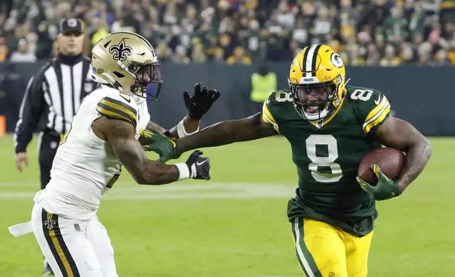 Green Bay Packers running back Josh Jacobs (8) carries against New Orleans Saints cornerback Will Harris during the first half of an NFL football game, Monday, Dec. 23, 2024, in Green Bay, Wis. (AP Photo/Mike Roemer)