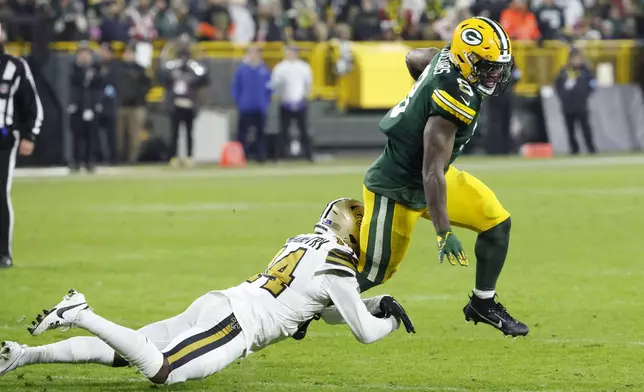 Green Bay Packers running back Josh Jacobs (8) carries against New Orleans Saints cornerback Kool-Aid McKinstry during the first half of an NFL football game, Monday, Dec. 23, 2024, in Green Bay, Wis. (AP Photo/Mike Roemer)