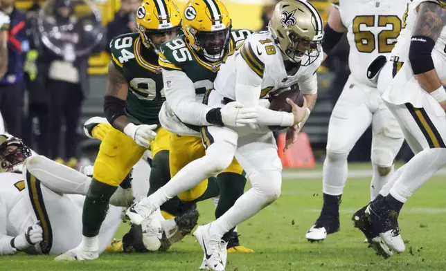 New Orleans Saints quarterback Spencer Rattler (18) is sacked by Green Bay Packers defensive tackle Devonte Wyatt (95) during the first half of an NFL football game, Monday, Dec. 23, 2024, in Green Bay, Wis. (AP Photo/Mike Roemer)