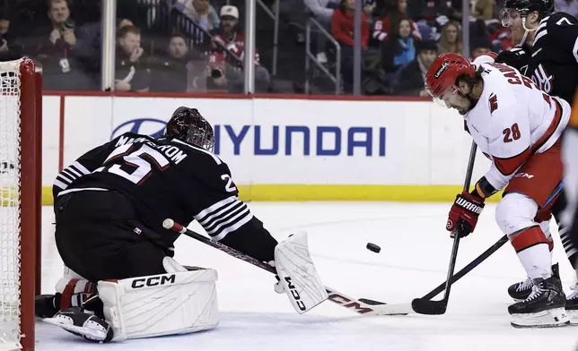 New Jersey Devils goaltender Jacob Markstrom (25) stops a shot by Carolina Hurricanes left wing William Carrier (28) in the first period of an NHL hockey game Friday, Dec. 27, 2024, in Newark, N.J. (AP Photo/Adam Hunger)