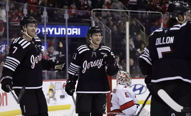 New Jersey Devils center Dawson Mercer (91) reacts with teammates after scoring a goal past Carolina Hurricanes goaltender Pyotr Kochetkov in the second period of an NHL hockey game Friday, Dec. 27, 2024, in Newark, N.J. (AP Photo/Adam Hunger)