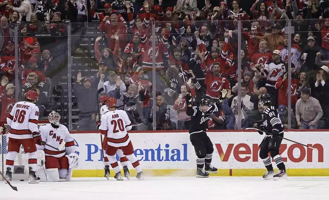 New Jersey Devils left wing Ondrej Palat, second right, celebrates after scoring a goal past Carolina Hurricanes goaltender Pyotr Kochetkov, second left, in the first period of an NHL hockey game Friday, Dec. 27, 2024, in Newark, N.J. (AP Photo/Adam Hunger)