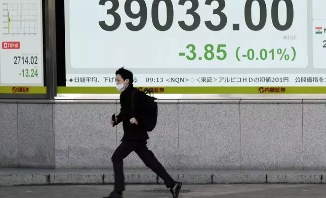 A person runs in front of an electronic stock board showing Japan's Nikkei index at a securities firm Wednesday, Dec. 25, 2024, in Tokyo. (AP Photo/Eugene Hoshiko)