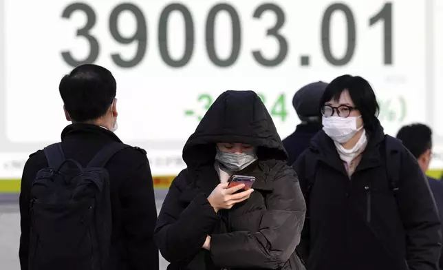 People walk in front of an electronic stock board showing Japan's Nikkei index at a securities firm Wednesday, Dec. 25, 2024, in Tokyo. (AP Photo/Eugene Hoshiko)