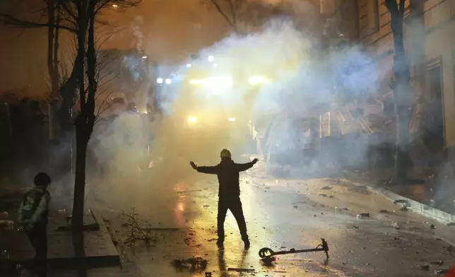 A demonstrator gestures as police block a street as protesters rally against the government's decision to suspend negotiations on joining the European Union for four years, outside the parliament's building in Tbilisi, Georgia, early Sunday, Dec. 1, 2024. (AP Photo/Zurab Tsertsvadze)