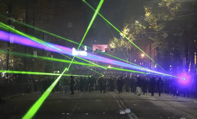 Demonstrators use lasers towards the police during a rally outside the parliament to protest against the government's decision to suspend negotiations on joining the European Union in Tbilisi, Georgia, on Tuesday, Dec. 3, 2024. (AP Photo/Zurab Tsertsvadze)