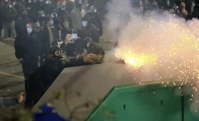 Demonstrators fire a firecracker towards police during a rally against the government's decision to suspend negotiations on joining the European Union for four years, outside the parliament's building in Tbilisi, Georgia, early Sunday, Dec. 1, 2024. (AP Photo/Zurab Tsertsvadze)