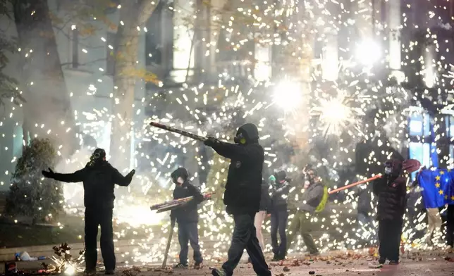 Demonstrators launch firecrackers during a protest against the government's decision to suspend negotiations on joining the European Union in Tbilisi, Georgia, early Wednesday, Dec. 4, 2024. (AP Photo/Pavel Bednyakov)