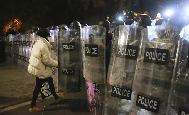 A woman speaks with police officers blocking a street to stop demonstrators protesting against the government's decision to suspend negotiations on joining the European Union in Tbilisi, Georgia, early Tuesday, Dec. 3, 2024. (AP Photo/Zurab Tsertsvadze)