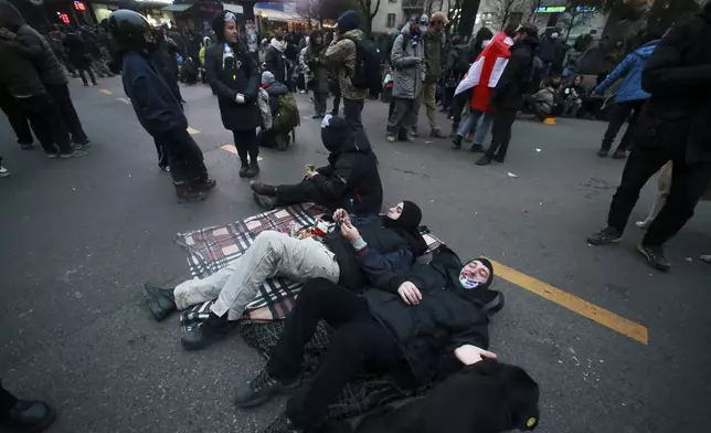 Protesters rest as they rally against the governments' decision to suspend negotiations on joining the European Union for four years, outside the parliament's building in Tbilisi, Georgia, early on Sunday, Dec. 1, 2024. (AP Photo/Zurab Tsertsvadze)