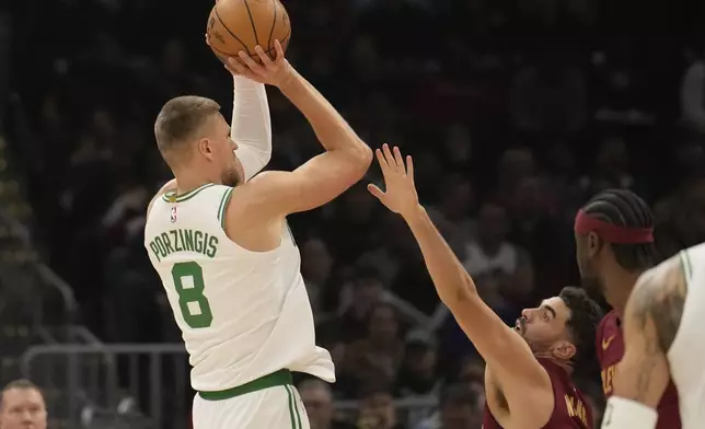 Boston Celtics center Kristaps Porzingis (8) shoots over Cleveland Cavaliers forward Georges Niang, right, in the first half of an NBA basketball game, Sunday, Dec. 1, 2024, in Cleveland. (AP Photo/Sue Ogrocki)