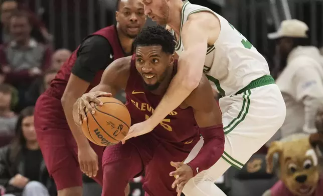 Cleveland Cavaliers guard Donovan Mitchell, front, steals the ball from Boston Celtics forward Sam Hauser, right, in the first half of an NBA basketball game, Sunday, Dec. 1, 2024, in Cleveland. (AP Photo/Sue Ogrocki)