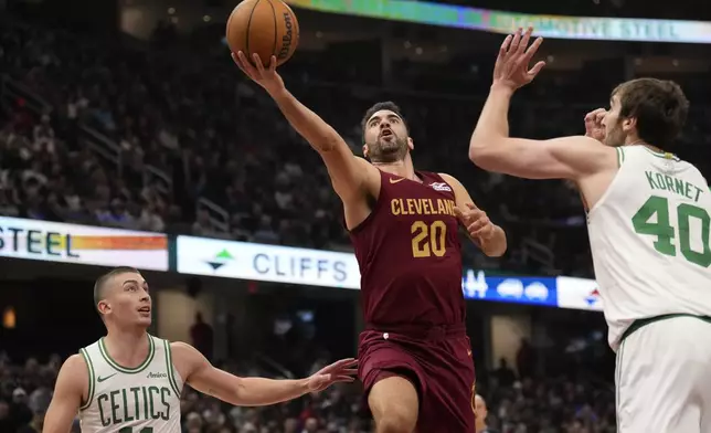 Cleveland Cavaliers forward Georges Niang (20) goes to the basket between Boston Celtics guard Payton Pritchard (11) and center Luke Kornet (40) in the first half of an NBA basketball game, Sunday, Dec. 1, 2024, in Cleveland. (AP Photo/Sue Ogrocki)