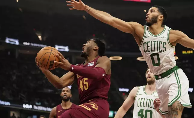 Cleveland Cavaliers guard Donovan Mitchell (45) goes to the basket in front of Boston Celtics forward Jayson Tatum (0) in the first half of an NBA basketball game, Sunday, Dec. 1, 2024, in Cleveland. (AP Photo/Sue Ogrocki)