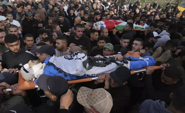 Mourners carry the bodies of killed Palestinians, some wrapped with the Islamic Jihad flag, during their funeral following the withdrawal of the Israeli army, in the West Bank city of Tulkarem, Thursday, Dec. 26, 2024. (AP Photo/Nasser Nasser)