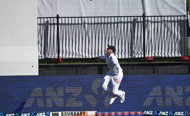 England's Harry Brook jumps over the boundary rope as he throws the ball in the air before taking a catch to dismiss New Zealand batsman Matt Henry during play on day one of the third cricket test between England and New Zealand in Hamilton, New Zealand, Saturday, Dec. 14, 2024. (Andrew Cornaga/Photosport via AP)