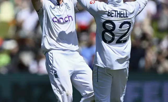 England bowler Matthew Potts, left, is congratulated by teammate Jacob Bethell after taking the wicket of New Zealand's Tom Latham during play on day one of the third cricket test between England and New Zealand in Hamilton, New Zealand, Saturday, Dec. 14, 2024. (Andrew Cornaga/Photosport via AP)