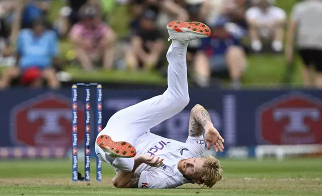 England's Ben Stokes falls over while bowling during play on day one of the third cricket test between England and New Zealand in Hamilton, New Zealand, Saturday, Dec. 14, 2024. (Andrew Cornaga/Photosport via AP)