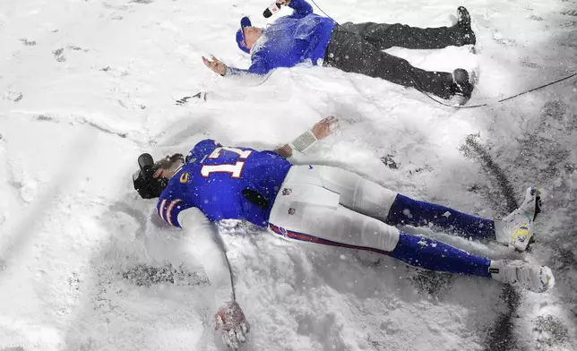 Buffalo Bills quarterback Josh Allen (17) and head coach Sean McDermott make snow angels on the field while being interviewed after an NFL football game against the San Francisco 49ers in Orchard Park, N.Y., Sunday, Dec. 1, 2024. (AP Photo/Adrian Kraus)