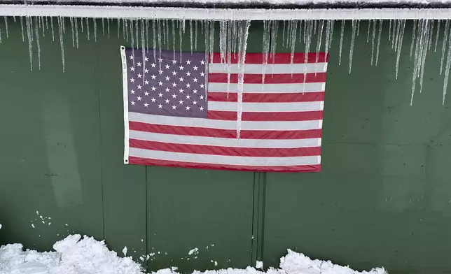 Icicles form over a flag during a snow storm, in Lowville, N.Y., on Sunday Dec, 1, 2024. (AP Photo/Cara Anna)