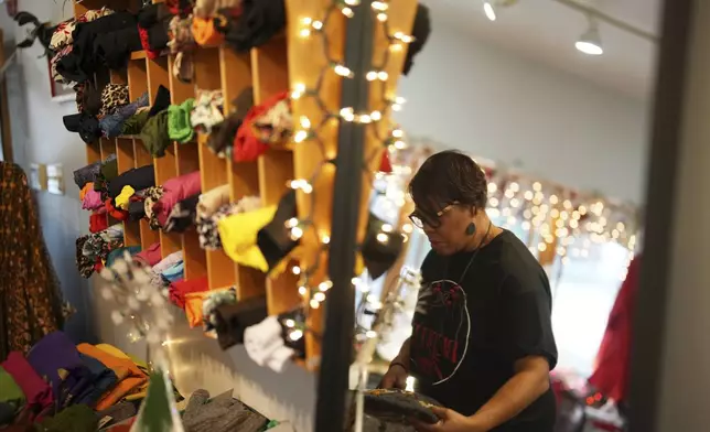 Claudia Averette lays out clothing at her shop, Between Friends Boutique, Wednesday, Dec. 11, 2024, in Philadelphia. (AP Photo/Matt Slocum)