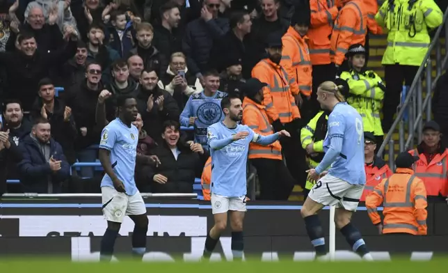 Manchester City's Bernardo Silva, center, is congratulated after scoring his side's opening goal during the English Premier League soccer match between Manchester City and Everton at the Etihad stadium in Manchester, Thursday, Dec. 26, 2024. (AP Photo/Rui Vieira)