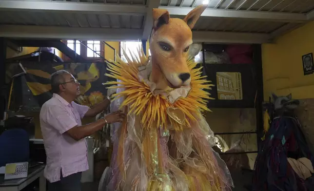 Workshop director Roberto Gomes inspects a caramelo dog costume at the Sao Clemente samba school, whose 2025 Carnival theme is animal abuse and abandonment, in Rio de Janeiro, Thursday, Nov. 28, 2024. (AP Photo/Silvia Izquierdo)