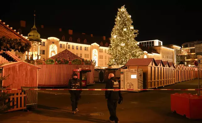 Security guards stand in front of a cordoned-off Christmas Market after a car crashed into a crowd of people, in Magdeburg, Germany, Saturday, Dec. 21, 2024. (AP Photo/Ebrahim Noroozi)