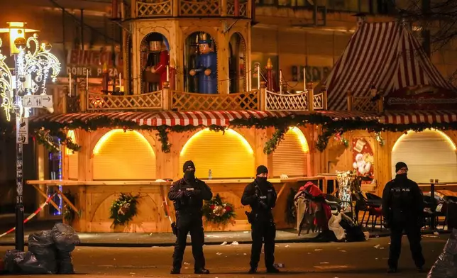 Security guards stand in front of a cordoned-off Christmas Market after a car crashed into a crowd of people, in Magdeburg, Germany, Saturday early morning, Dec. 21, 2024. (AP Photo/Ebrahim Noroozi)