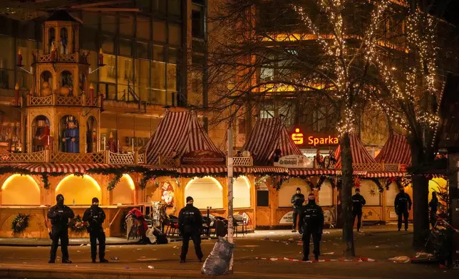 Security guards stand in front of a cordoned-off Christmas Market after a car crashed into a crowd of people, in Magdeburg, Germany, Saturday early morning, Dec. 21, 2024. (AP Photo/Ebrahim Noroozi)