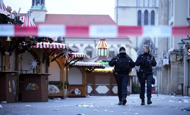 Police officers patrol a cordoned-off area at a Christmas Market, where a car drove into a crowd on Friday evening, in Magdeburg, Germany, Saturday, Dec. 21, 2024. (AP Photo/Ebrahim Noroozi)