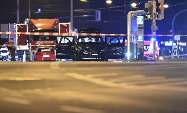 A damaged car sits with its doors open after a driver plowed into a busy Christmas market in Magdeburg, Germany, early Saturday, Dec. 21, 2024. (Hendrik Schmidt/dpa via AP)