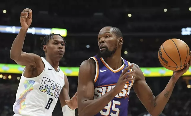 Phoenix Suns forward Kevin Durant, right, looks to pass the ball as Denver Nuggets forward Peyton Watson defends in the second half of an NBA basketball game Monday, Dec. 23, 2024, in Denver. (AP Photo/David Zalubowski)