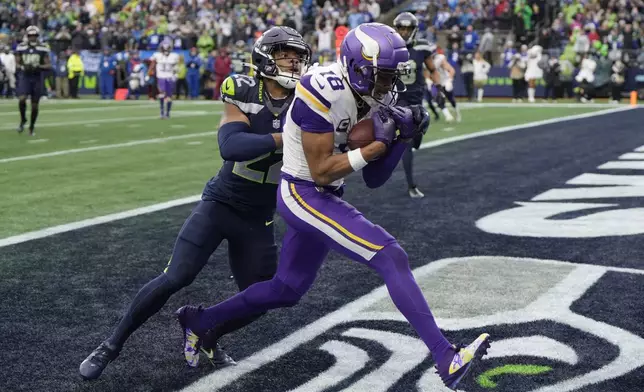 Minnesota Vikings wide receiver Justin Jefferson (18) catches a 14-yard touchdown pass ahead of Seattle Seahawks cornerback Tre Brown (22) during the first half of an NFL football game, Sunday, Dec. 22, 2024, in Seattle. (AP Photo/Stephen Brashear)